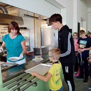 Usměvavá paní kuchařka nandává polévku